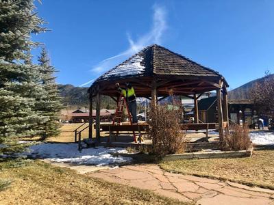 Maintenance staff on ladder hanging holiday lights on gazebo
