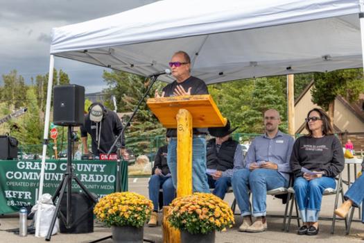 The Town Mayor gives a speech at a podium under a shade tent